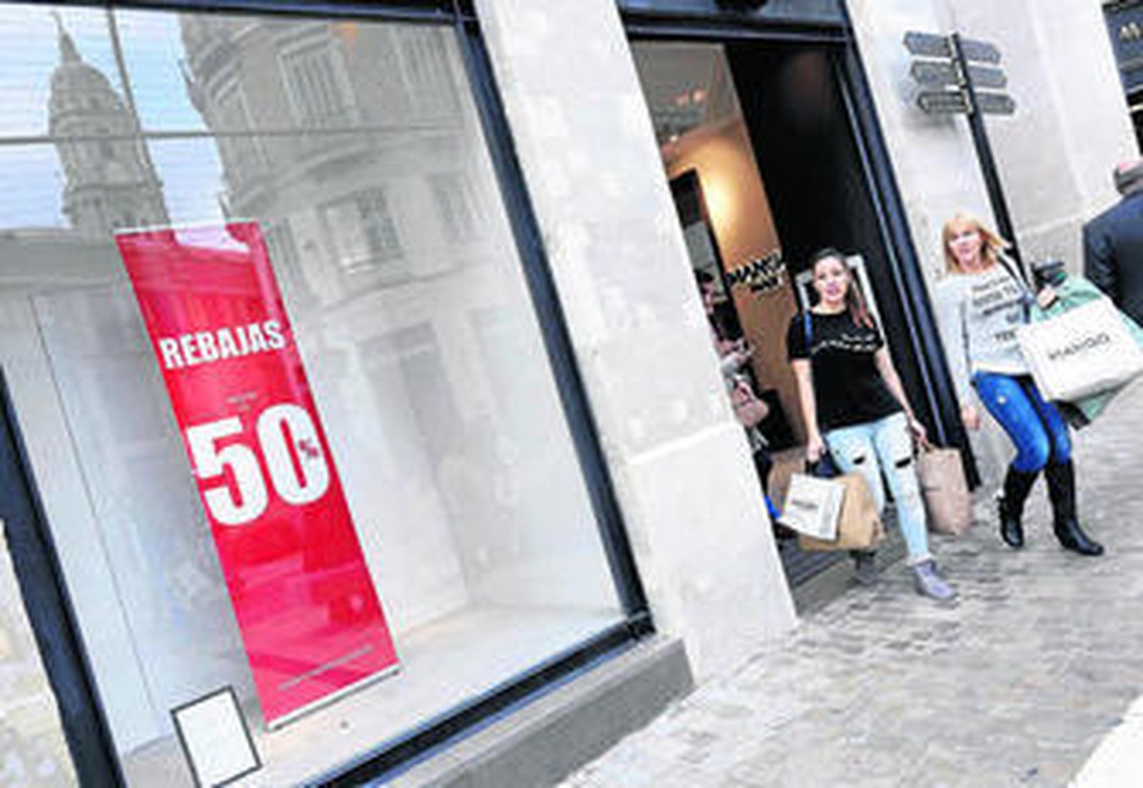 Dos mujeres salen de una tienda de la calle Larios con bolsas.