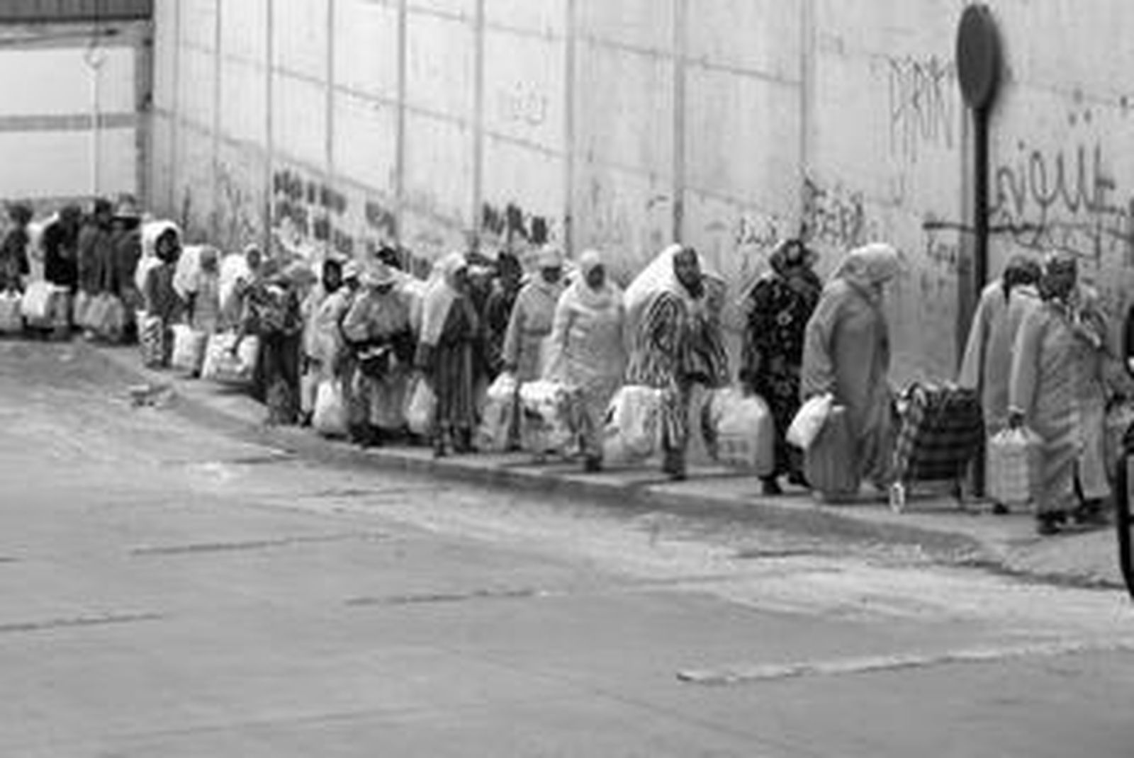 Porteadoras caminan en fila india por la cuesta que conduce al paso de El Biutz, el pasado jueves, dentro del polígono ceutí de El Tarajal.