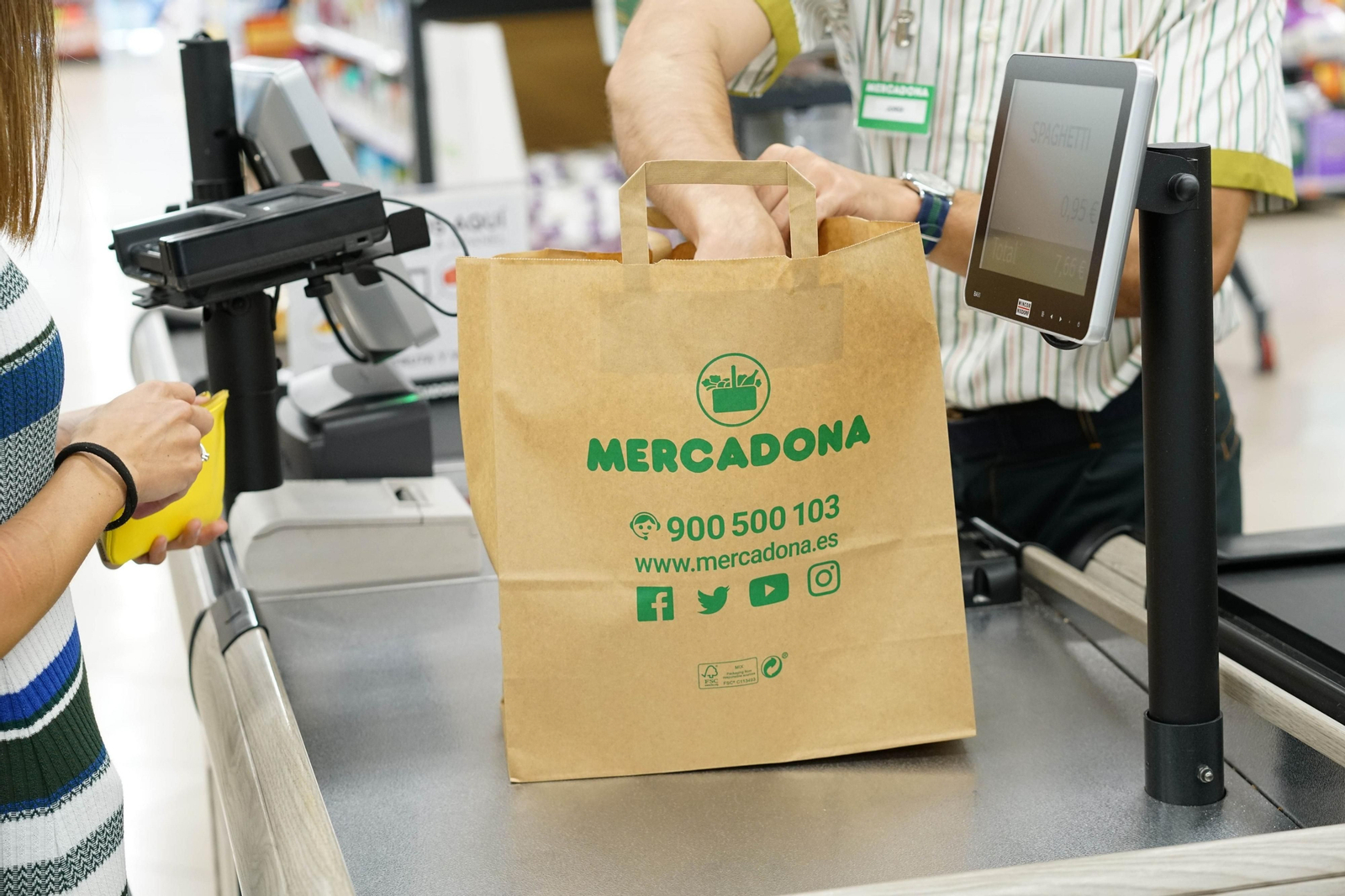 Un cajero coloca la compra dentro de una bolsa de Mercadona