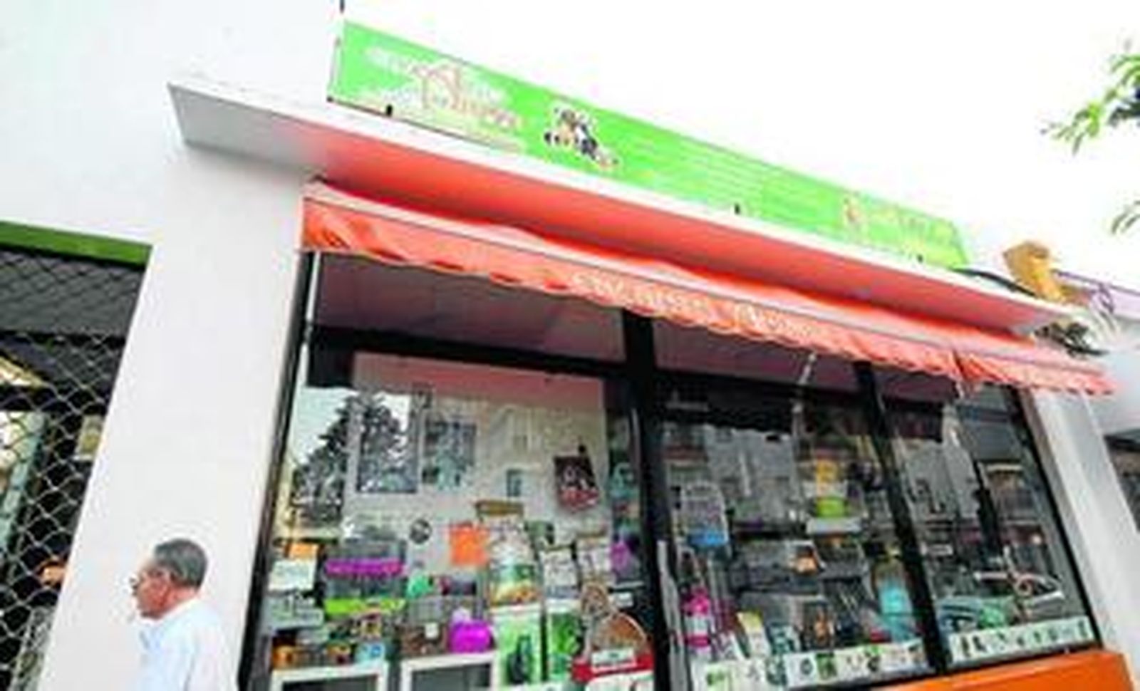 Un hombre pasa junto al escaparate de una tienda de mascotas repleto de artículos.