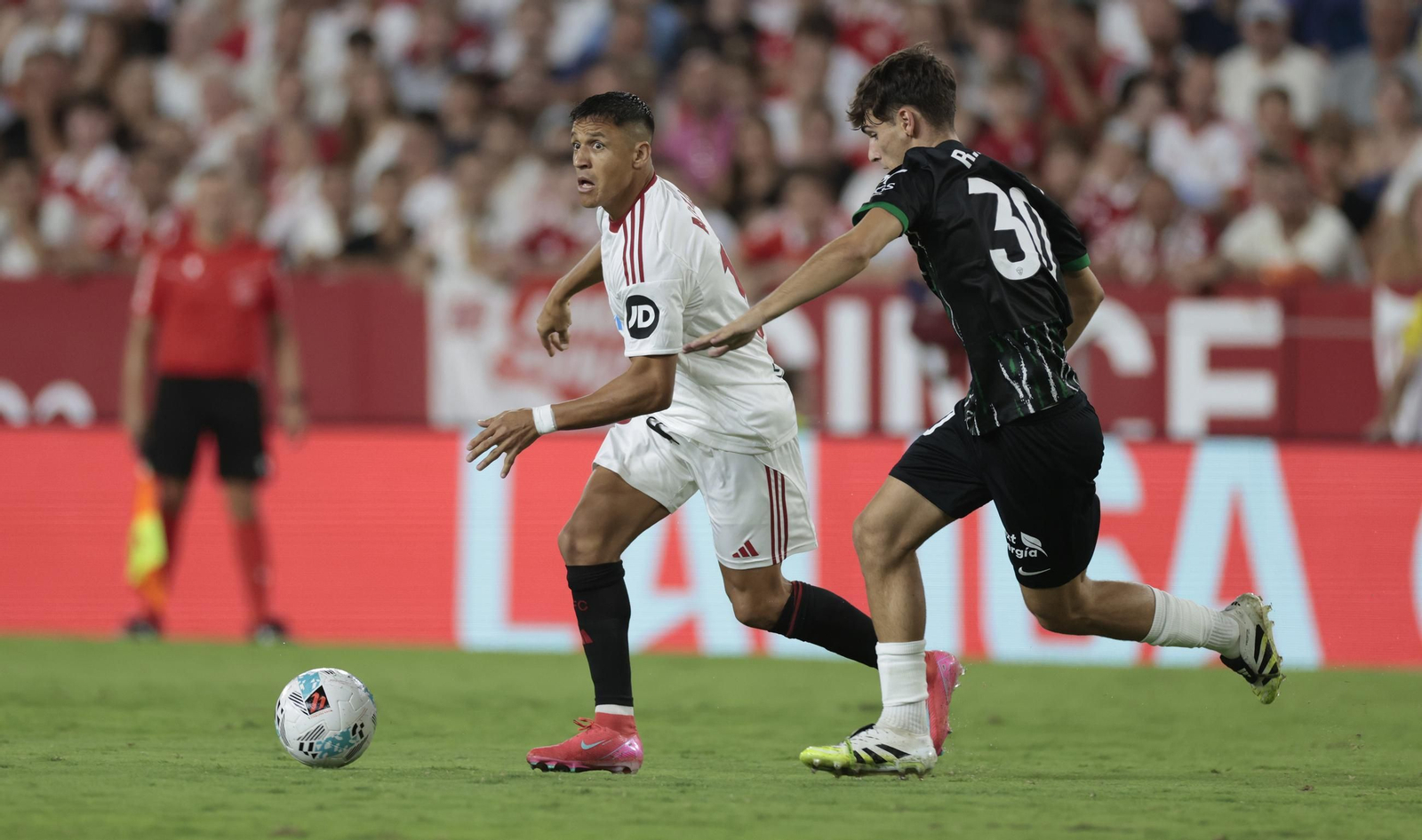 Alexis Sánchez conduce la pelota con la cabeza levantada para buscar a un compañero.