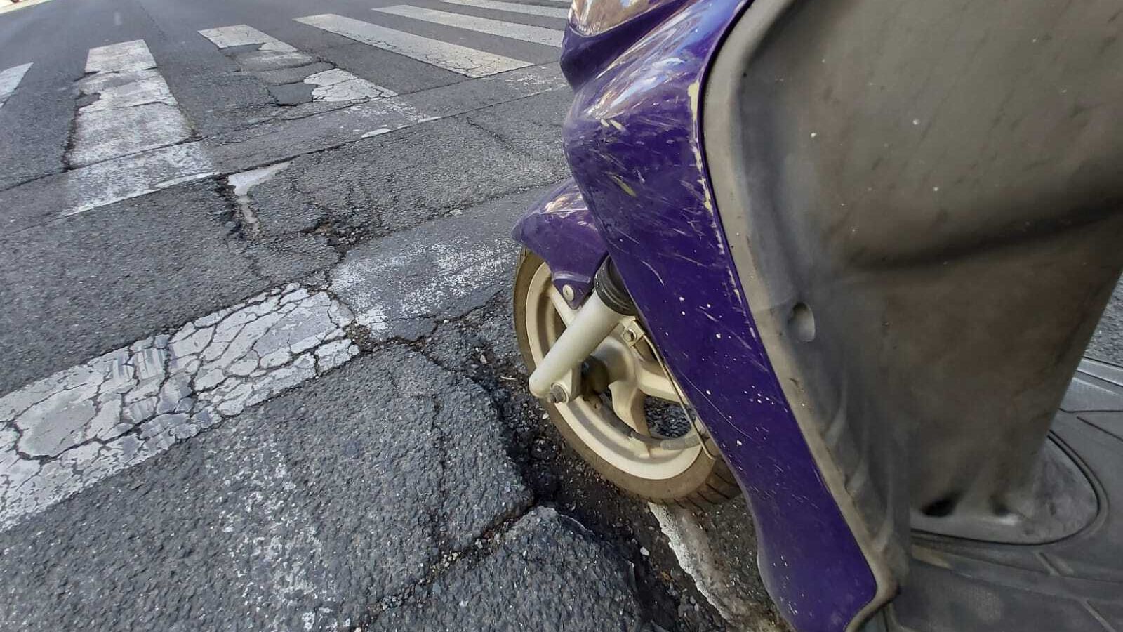 Una motocicleta parada sobre un bache de una calle.