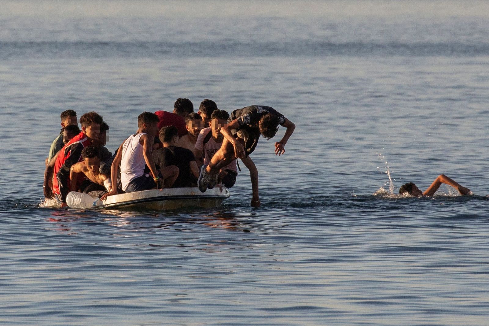 Varios menores migrantes lanzándose al agua para alcanzar la playa ceutí de El Tarajal.