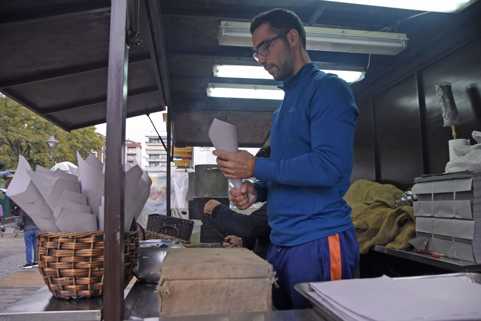 Un vendedor sostiene un cartucho de castañas asadas en un puesto.