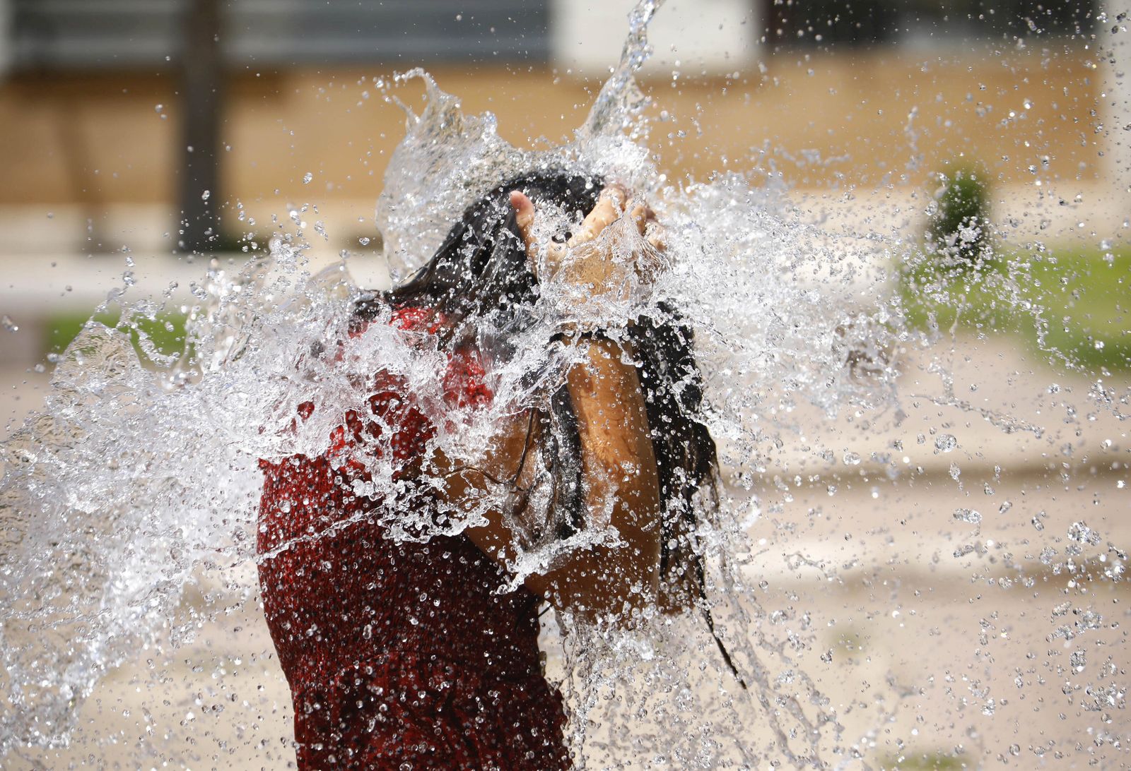 Una joven se refresca en una fuente en Córdoba.