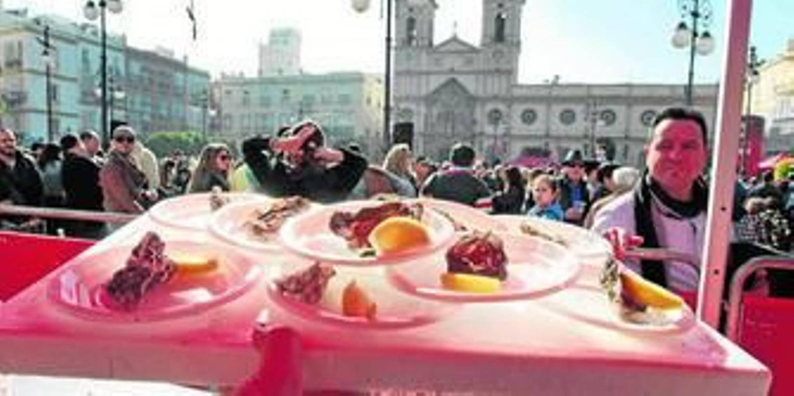 Platos de ostiones repartidos en la plaza de San Antonio con la iglesia parroquial al fondo.
