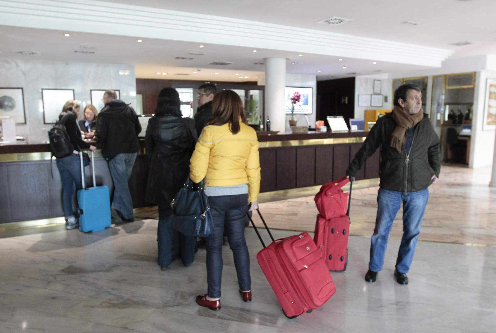 Retrospectiva de turistas haciendo cola para registrarse en un establecimiento hotelero.