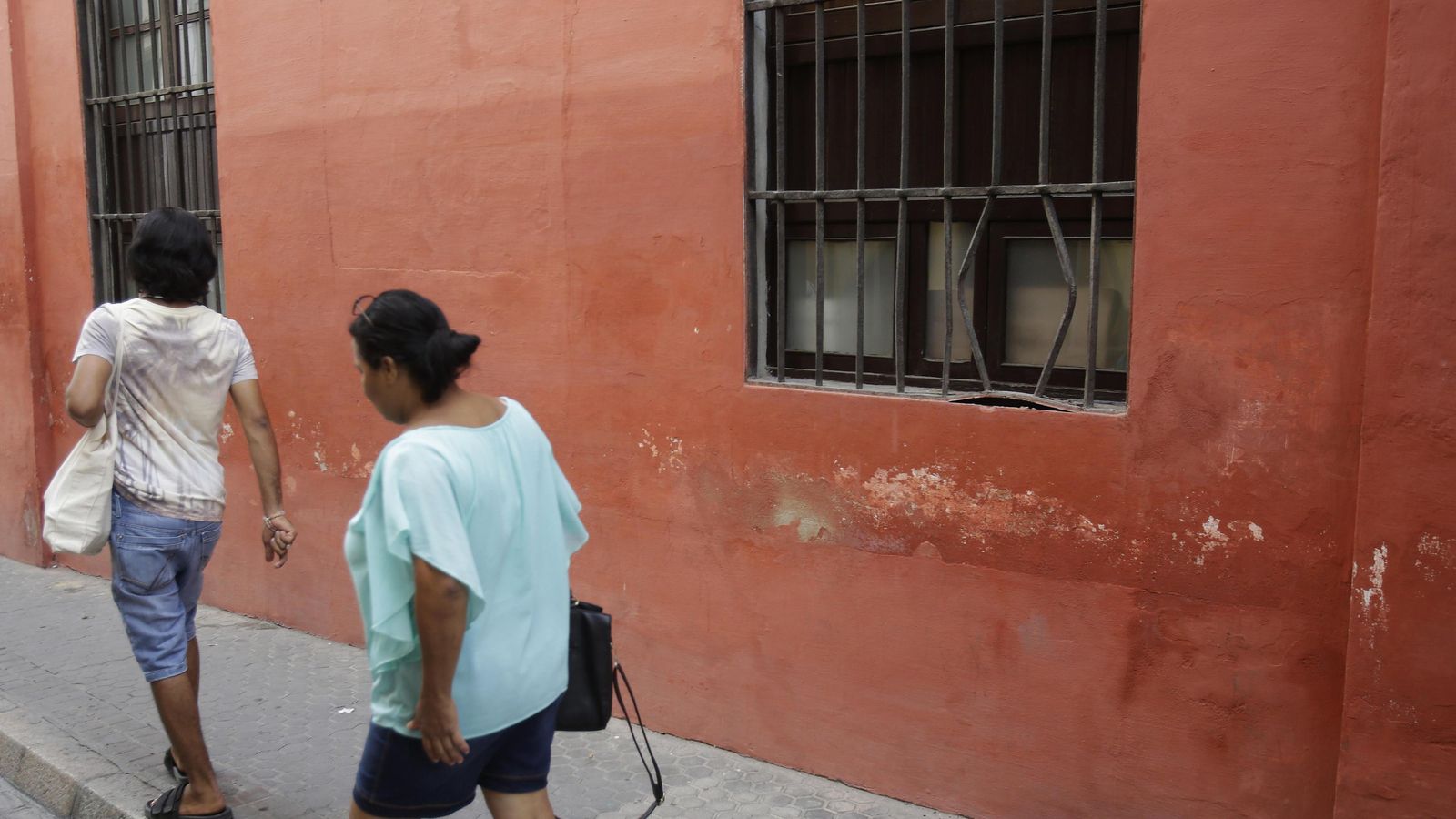 Dos personas pasan junto a una de las ventanas forzadas.
