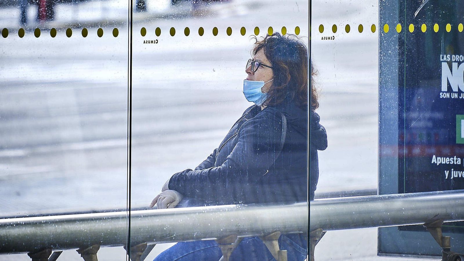 Una mujer espera en la parada del autobús urbano.