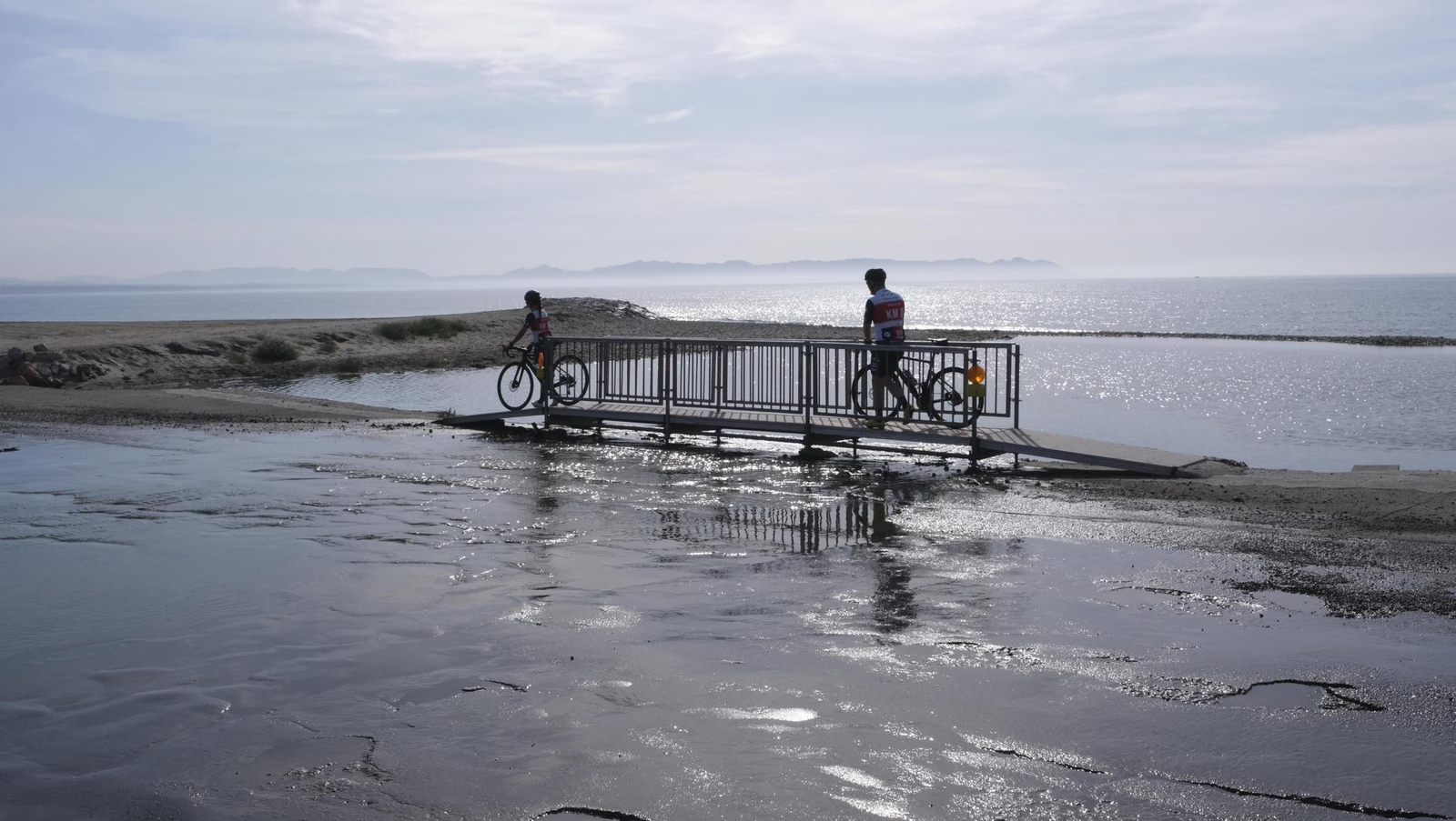 Dos ciclistas atraviesan la pasarela instalada por el Ayuntamiento para poder cruzar por la rambla de Costacabana.