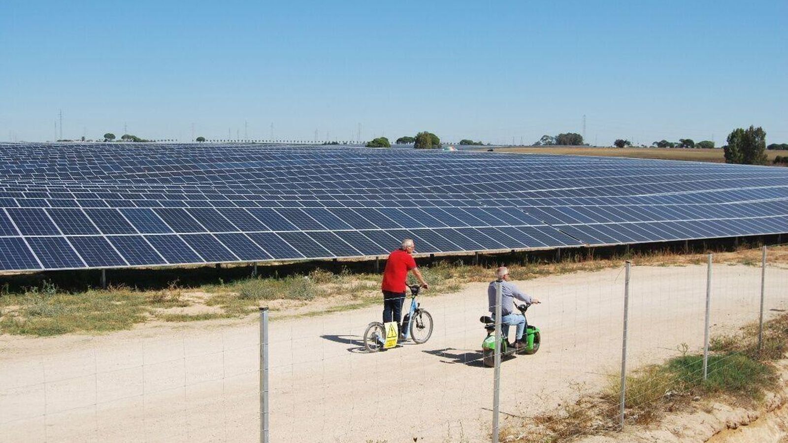 Dos personas montan en bicicleta junto a una planta fotovoltaica Dos personas montan en bicicleta junto a una planta fotovoltaica