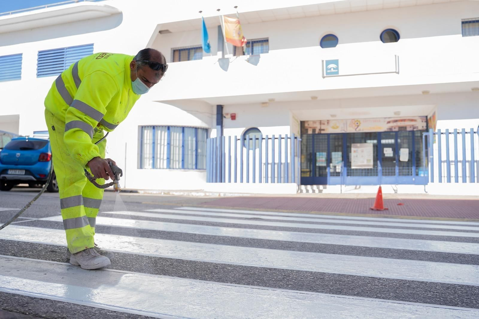 Un operario pinta un paso de peatón ante el colegio Servando Camúñez.