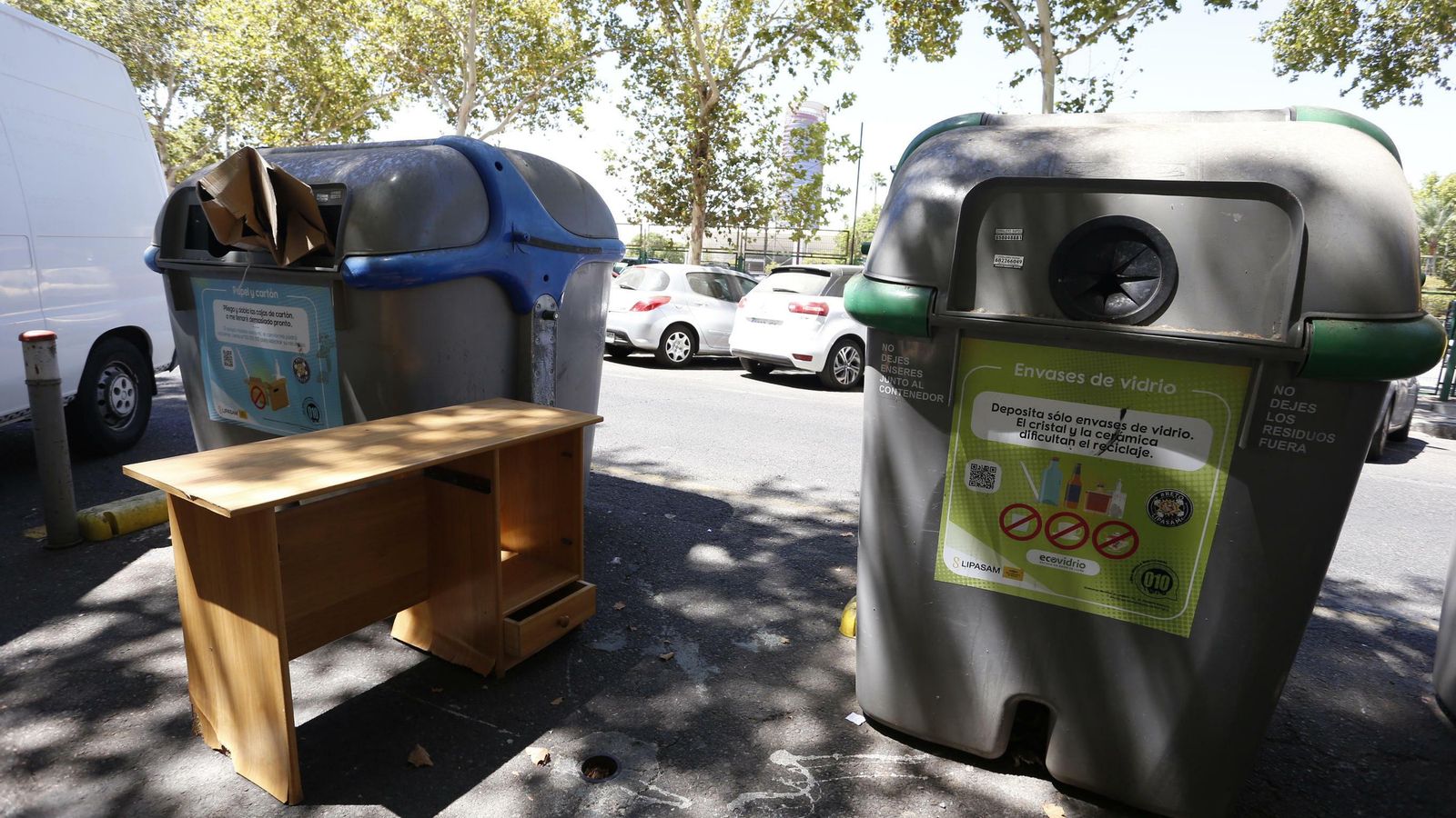 Una mesa abandonada junto a un contenedor.