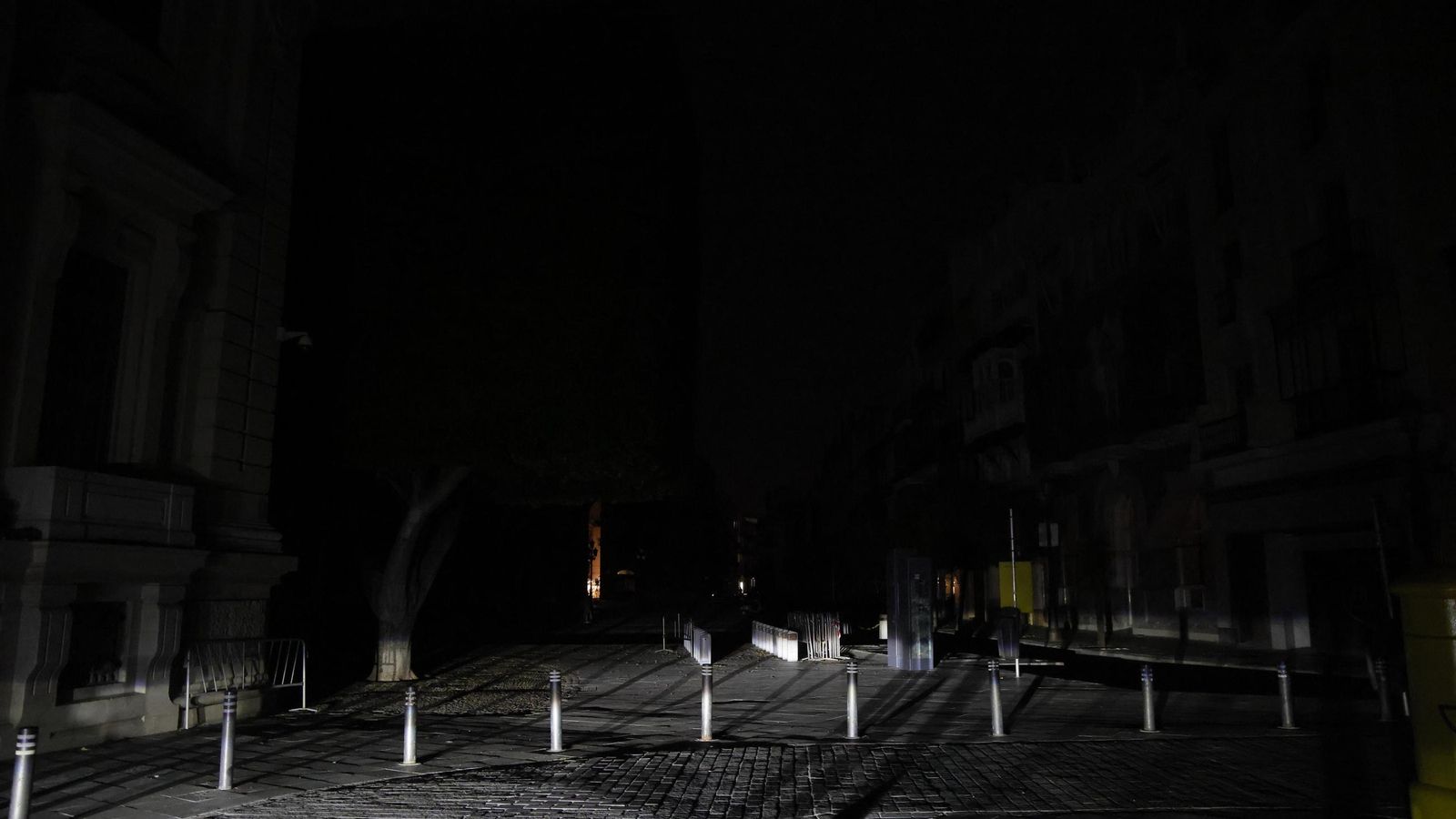 La fachada del Banco de España, con la única luz de los faros de un coche.