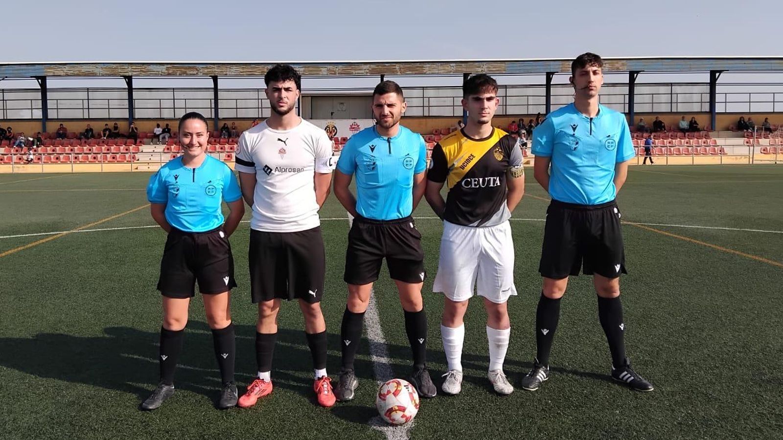 Los capitanes de ambos equipos posan junto al trío arbitral antes del comienzo del encuentro en La Cañada.