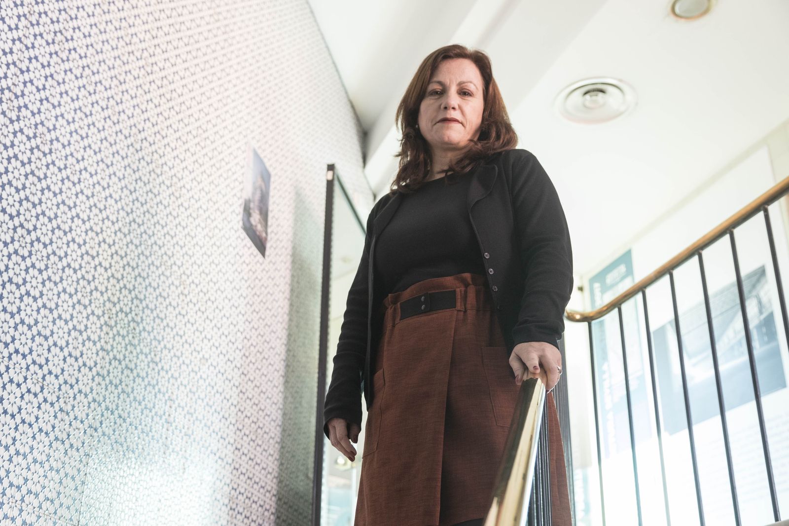 La decana Cristina Murillo en la majestuosa escalera del colegio. A la derecha en una exposición en la sede.