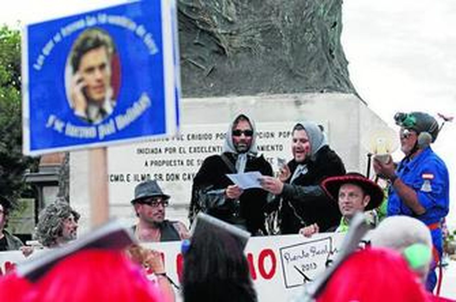 Componentes de la plataforma Por un carnaval libre leen el romancero bajo la estatua de Moret.