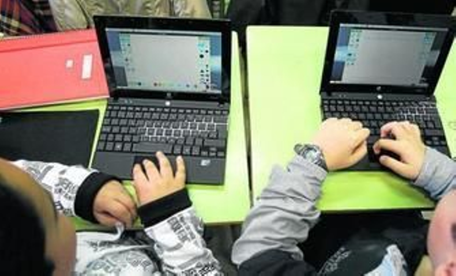 Dos alumnos, con sus ordenadores portátiles en clase.