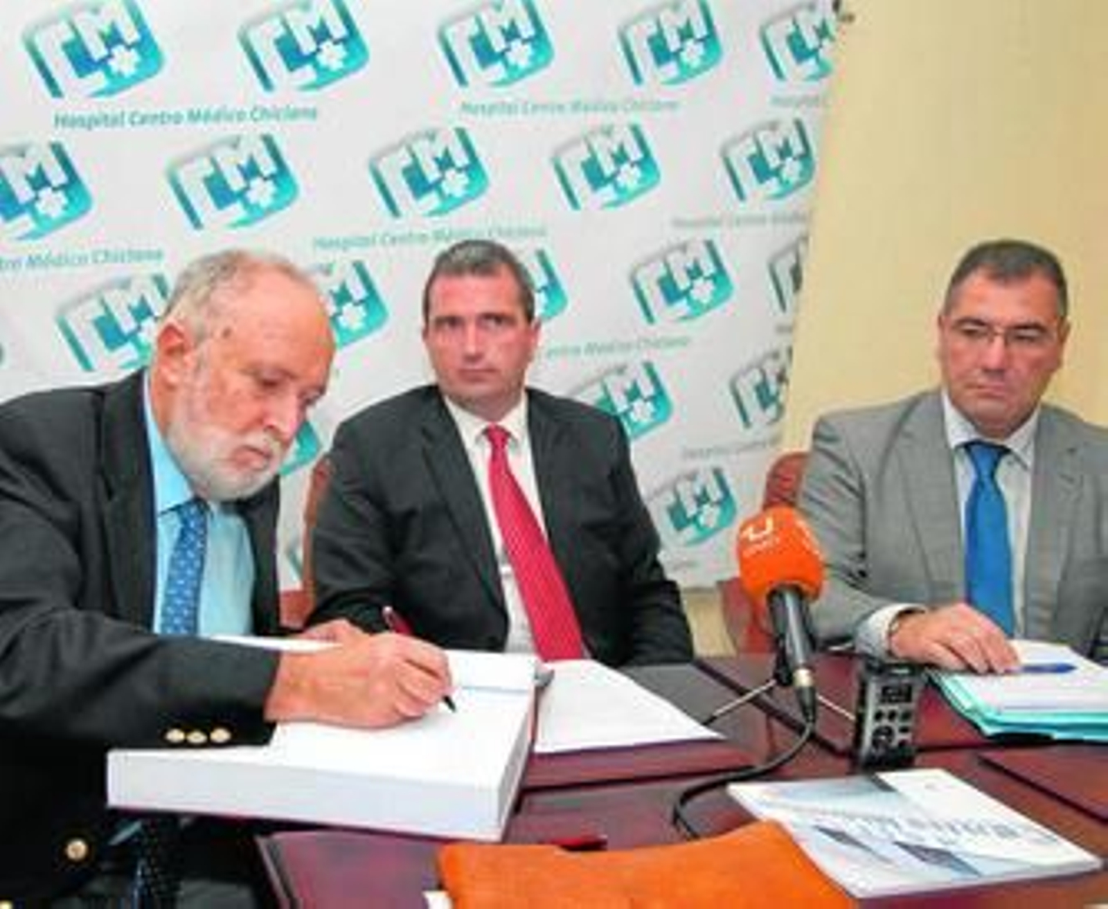 Juan Antonio Repeto firma en el Libro de Honor del Centro Médico ante Carlos Bascuas y Antonio Soto.