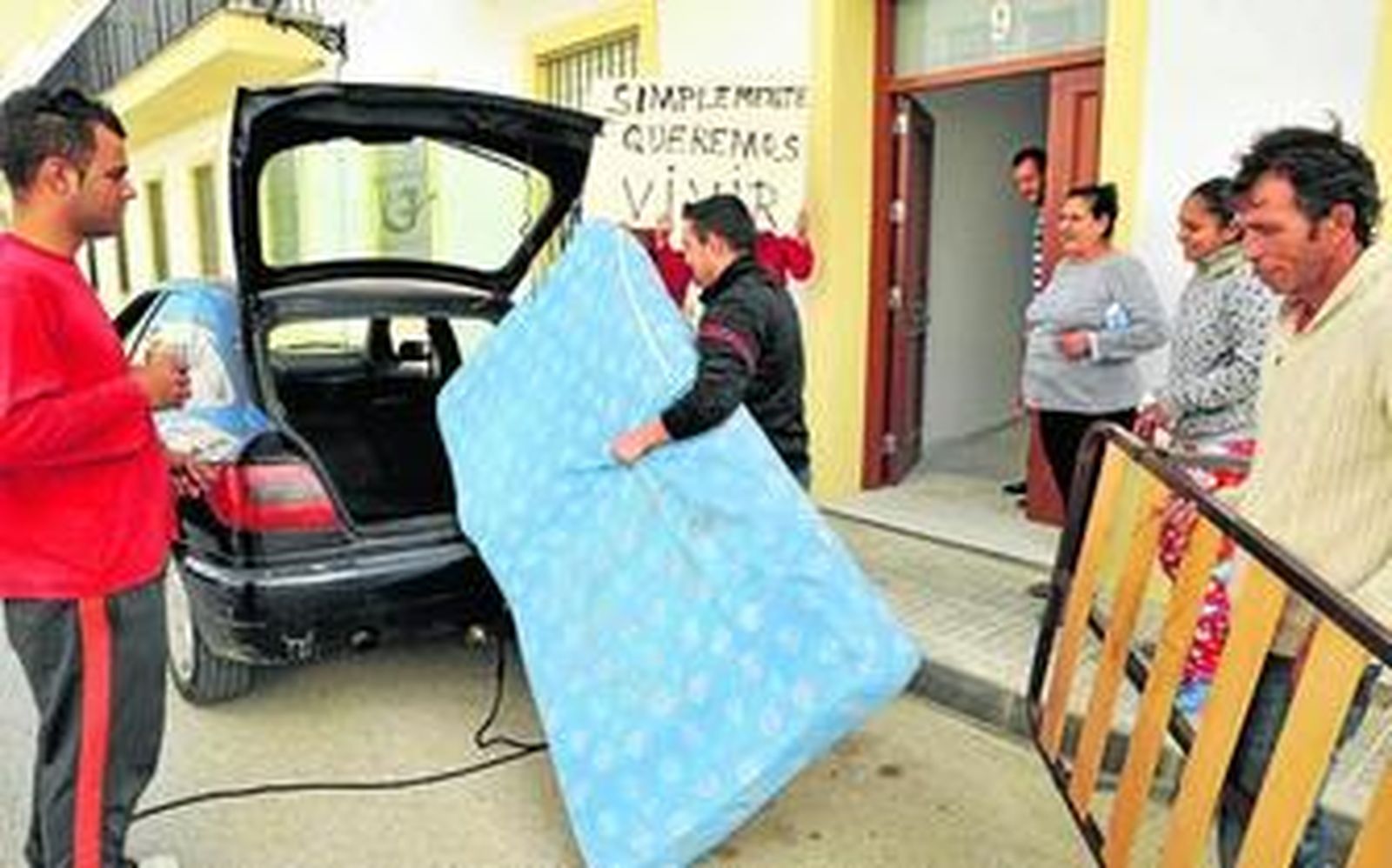 Varios vecinos trasladando, ayer, por la mañana, enseres a la promoción ocupada de 39 viviendas vacías, hasta donde se han mudado para vivir.