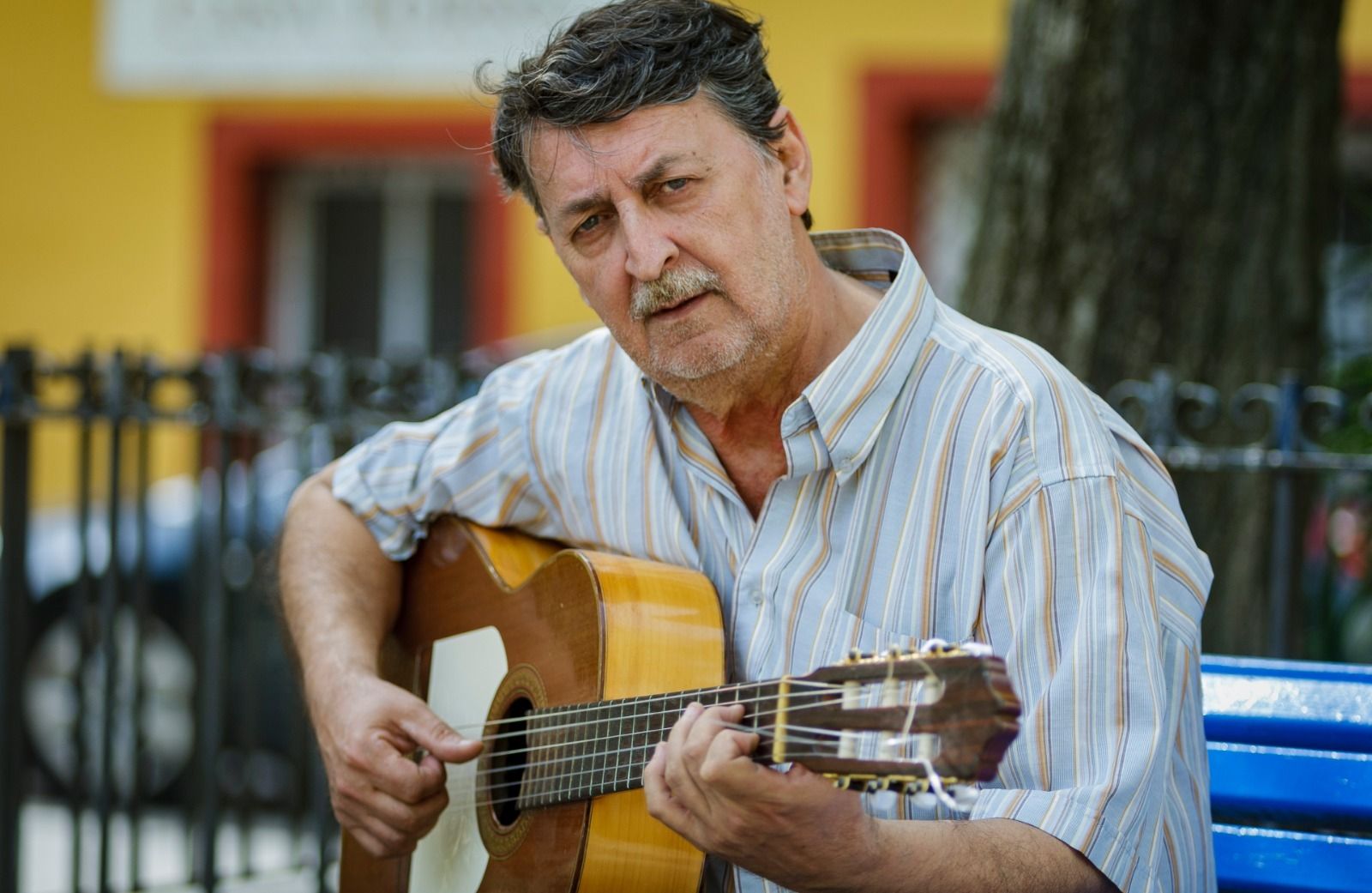 José Luis Bustelo con su guitarra en la plaza del barrio de Puntales.