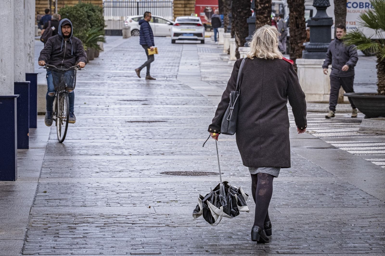 Una mujer, con su paraguas cerrado, por Cádiz.