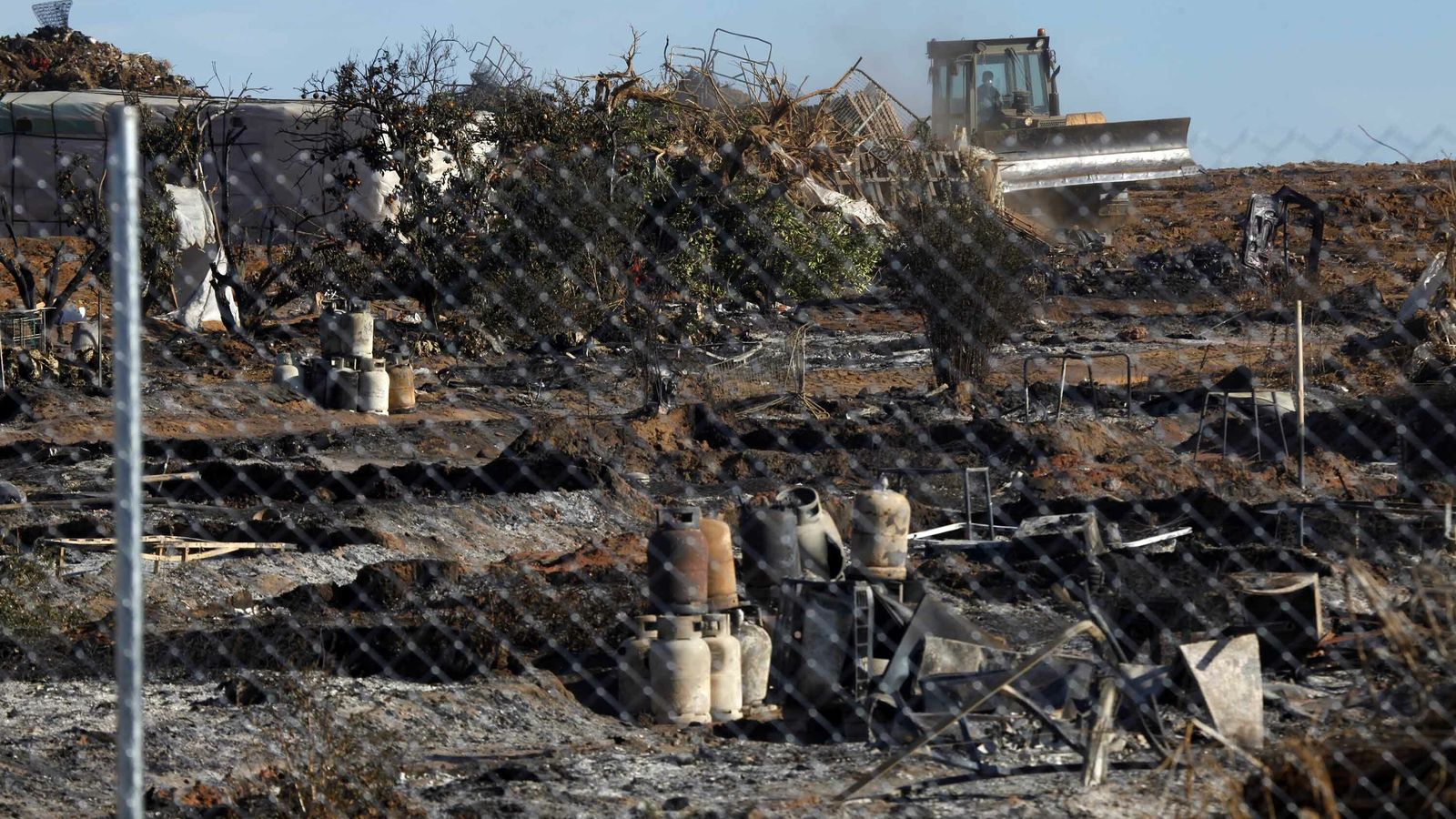 Las máquinas desmantela el asentamiento calcinado.
