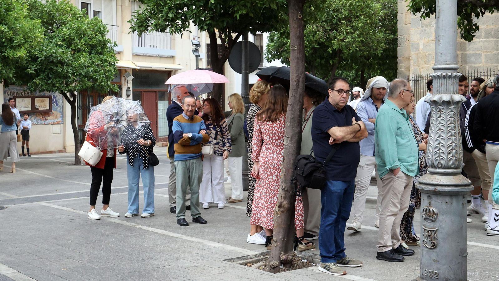 Personas, algunas con paraguas, aguardando cola en la iglesia de San Miguel en Jerez