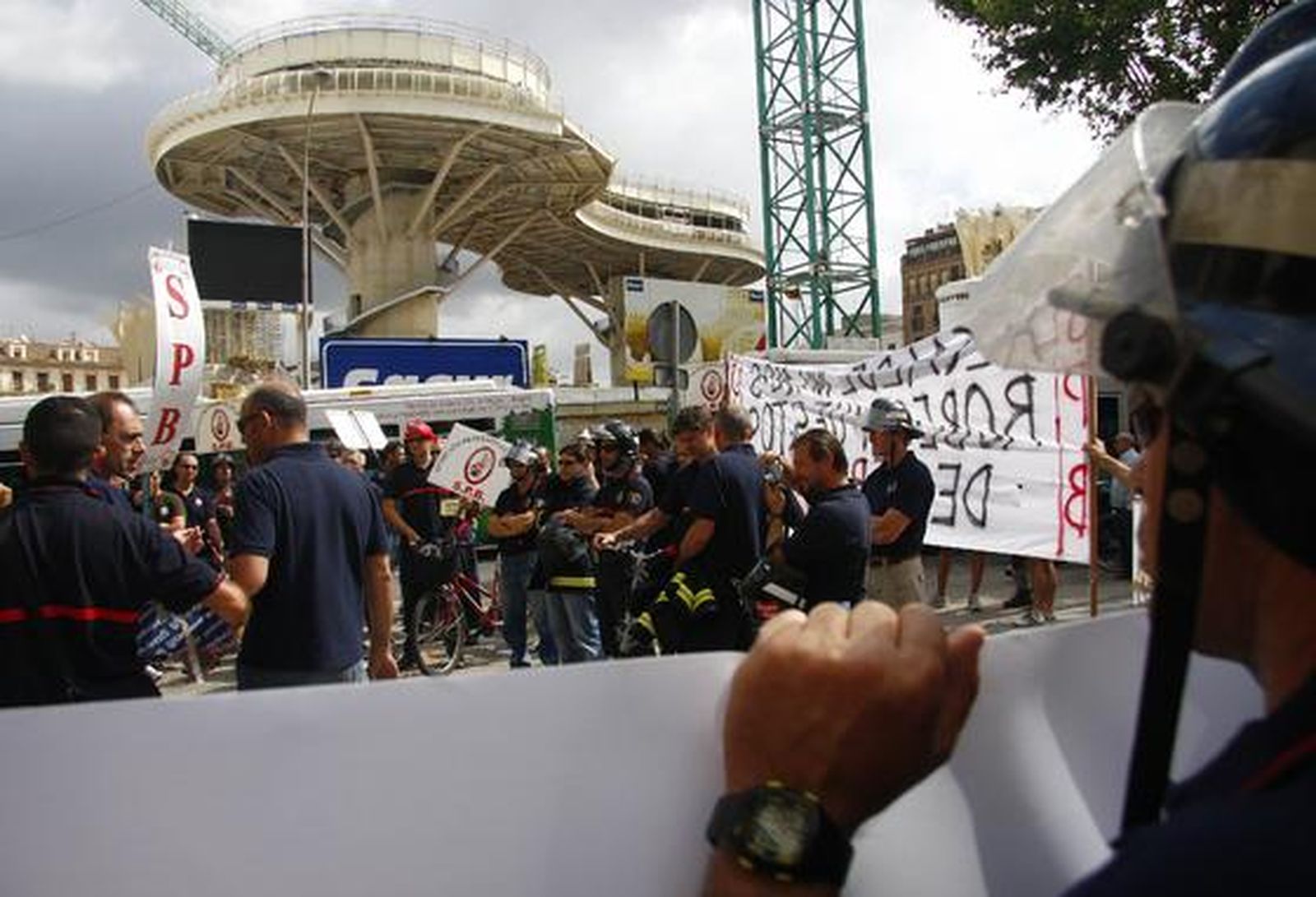 Varios bomberos sostienen una pancarta frente a las obras del Metropol Parasol.

Foto: B. Vargas