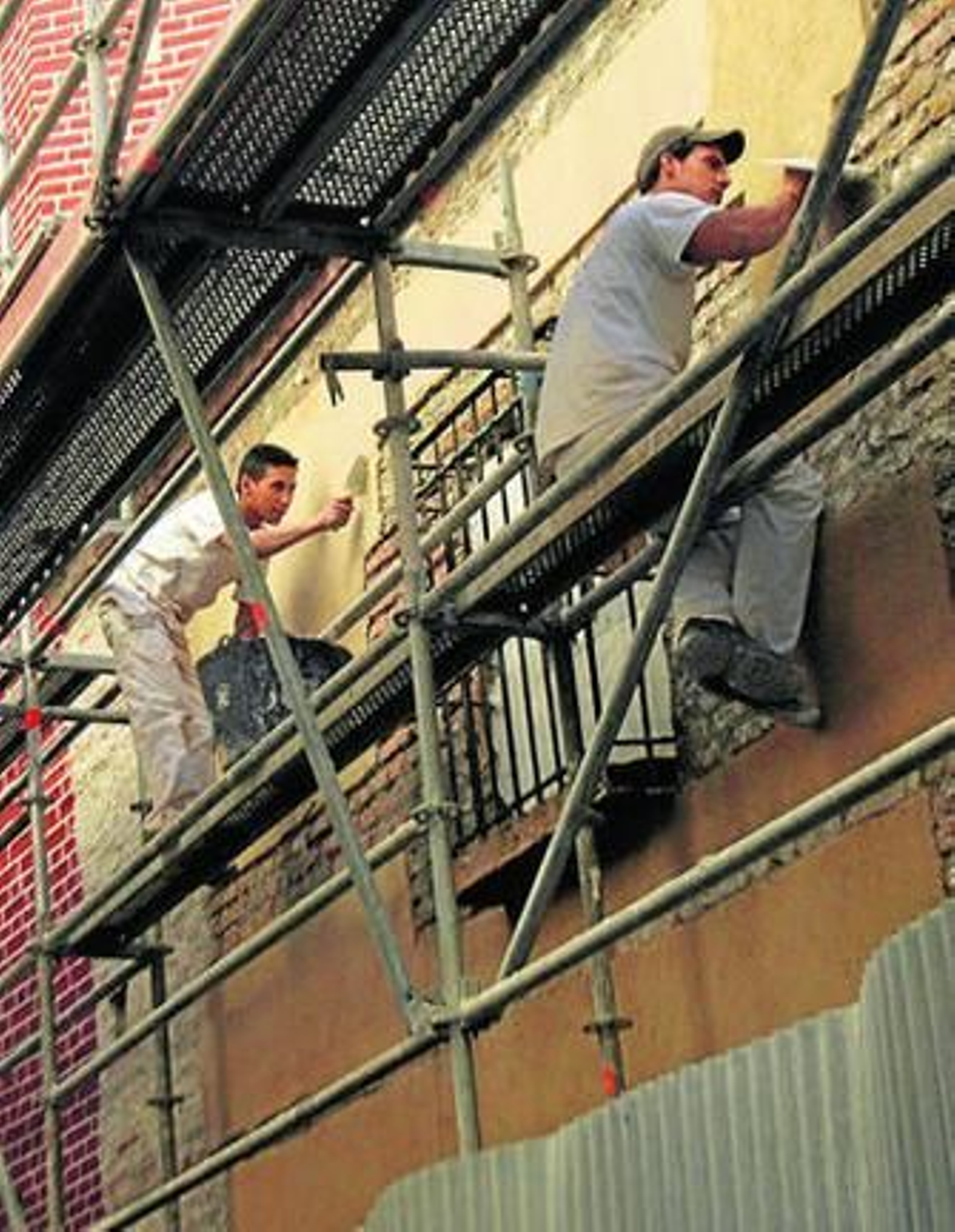 Dos jóvenes trabajan sobre un andamio.