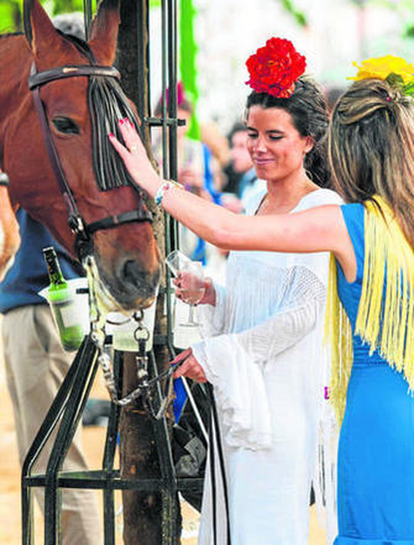 Dos jóvenes vestidas de flamenca acarician un caballo ayer, en la Feria.