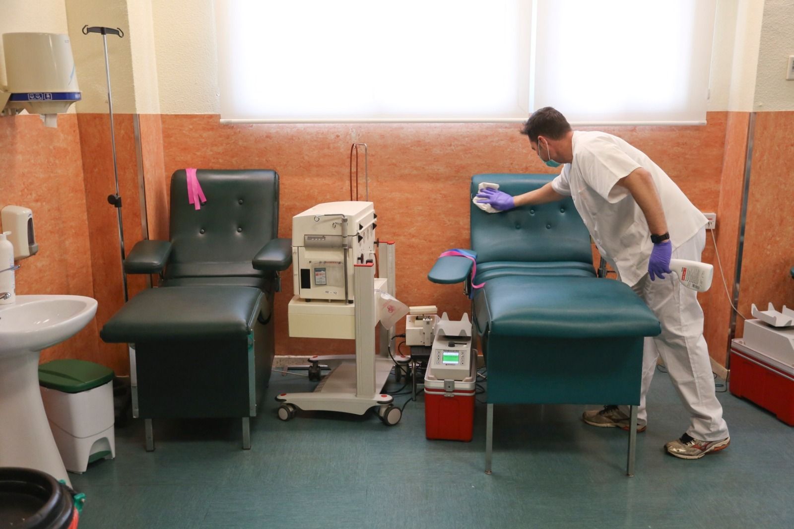 Un enfermero limpiando una camilla.