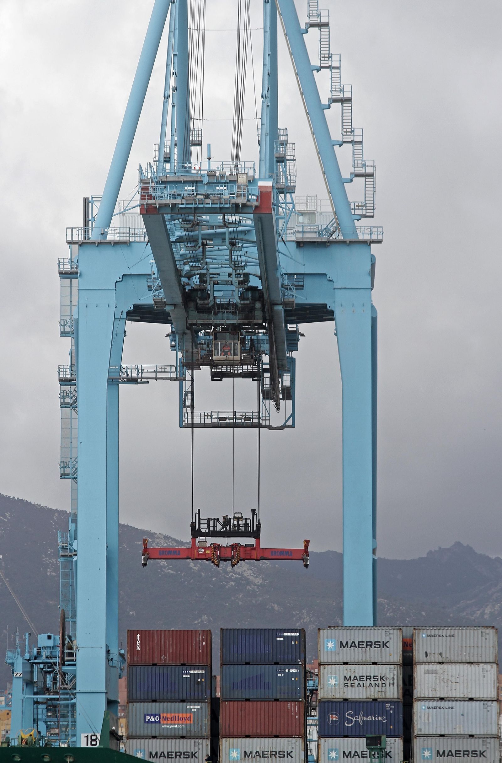 Un estibador se dispone a izar contenedores desde la cabina de una grúa en el puerto de Algeciras.