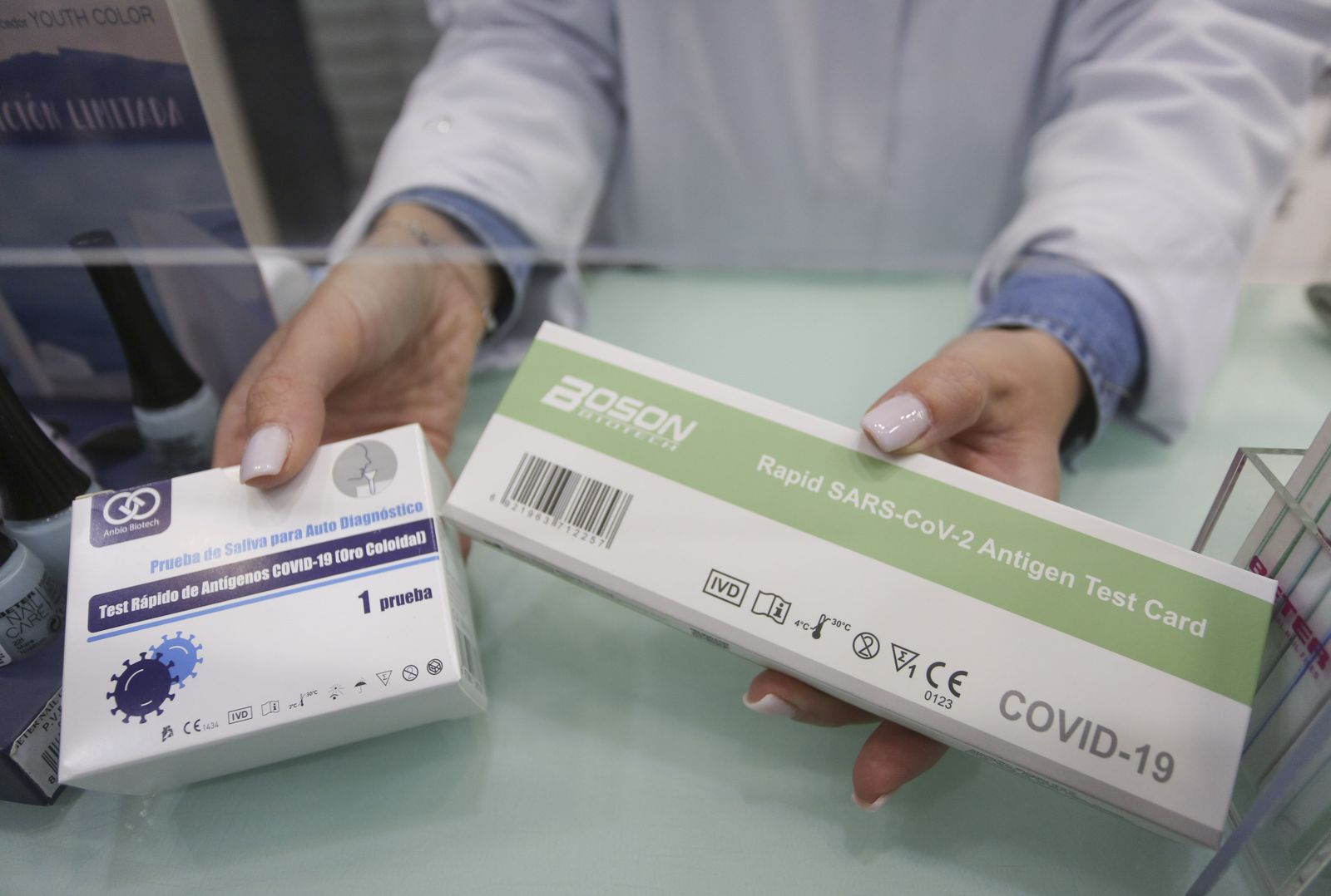 Una farmacéutica muestra cajas de test de antígenos.