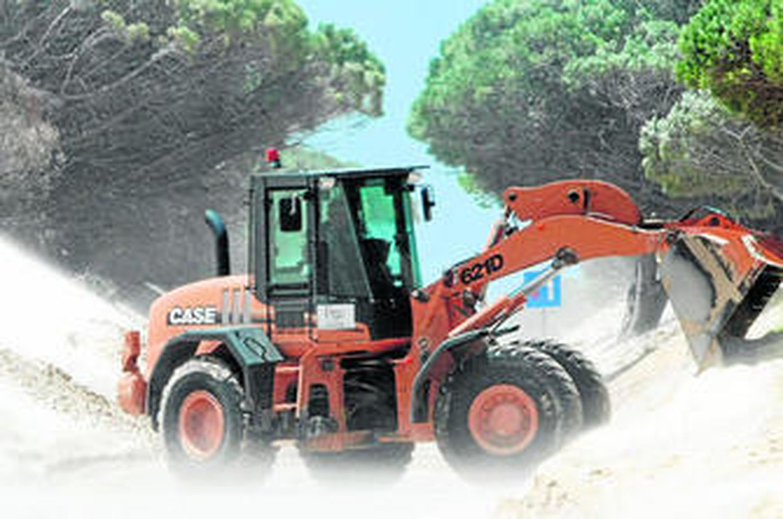 Una máquina retira arena de la duna de Valdevaqueros para despejar la carretera a Paloma Baja, el pasado junio.