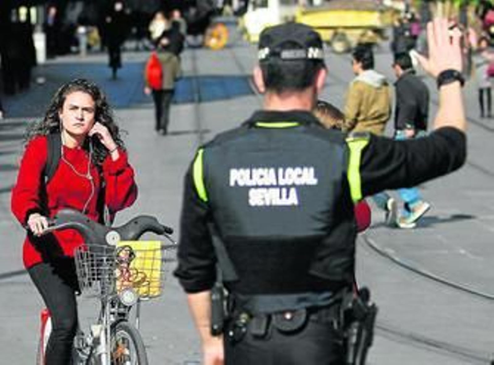 Un policía da el alto a una mujer en bicicleta y con auriculares en Sevilla, donde se multa desde noviembre.