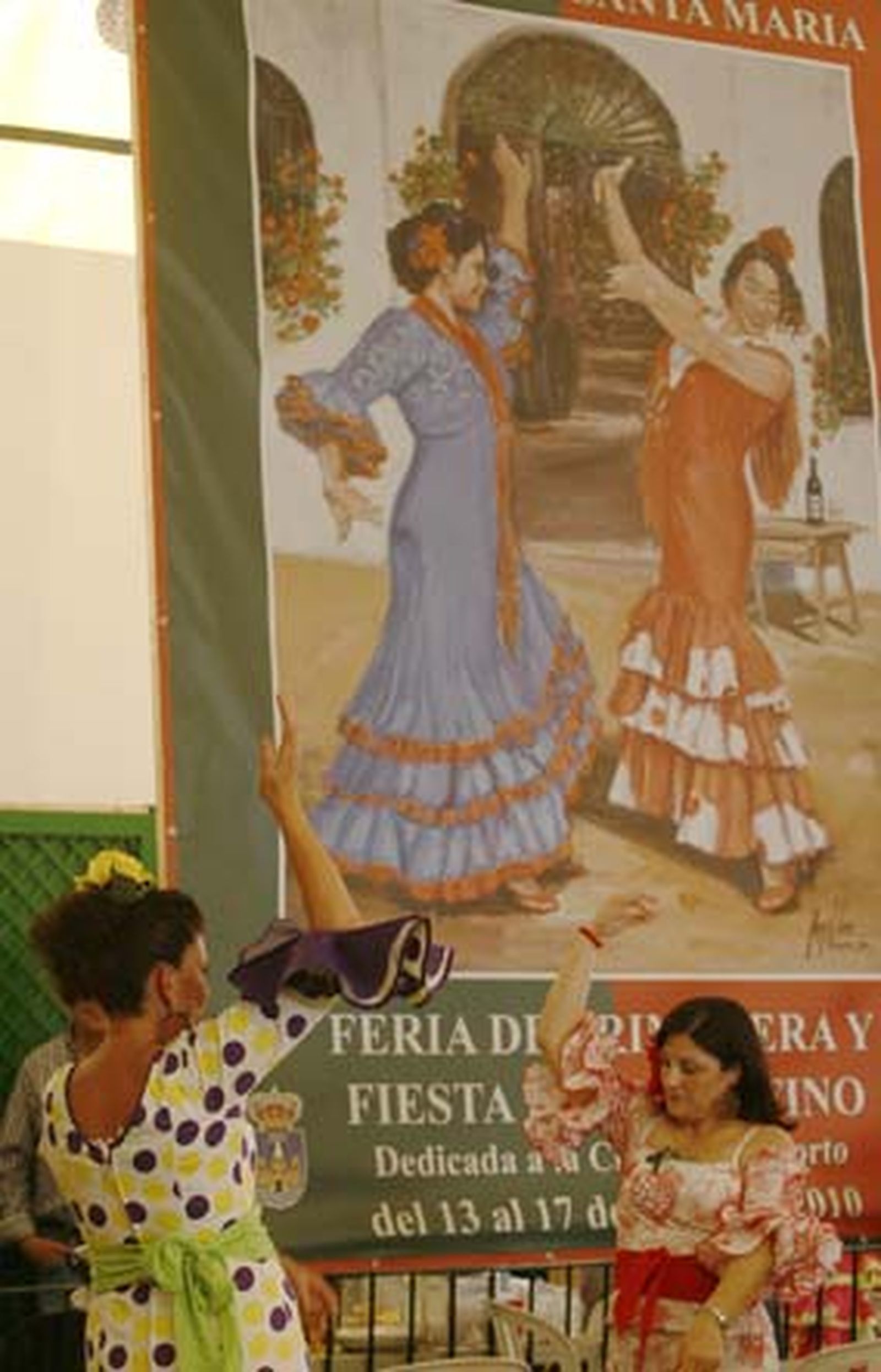 Dos mujeres bailan bajo un gran cartel de la Feria 2010.  Foto: Borja Benjumeda