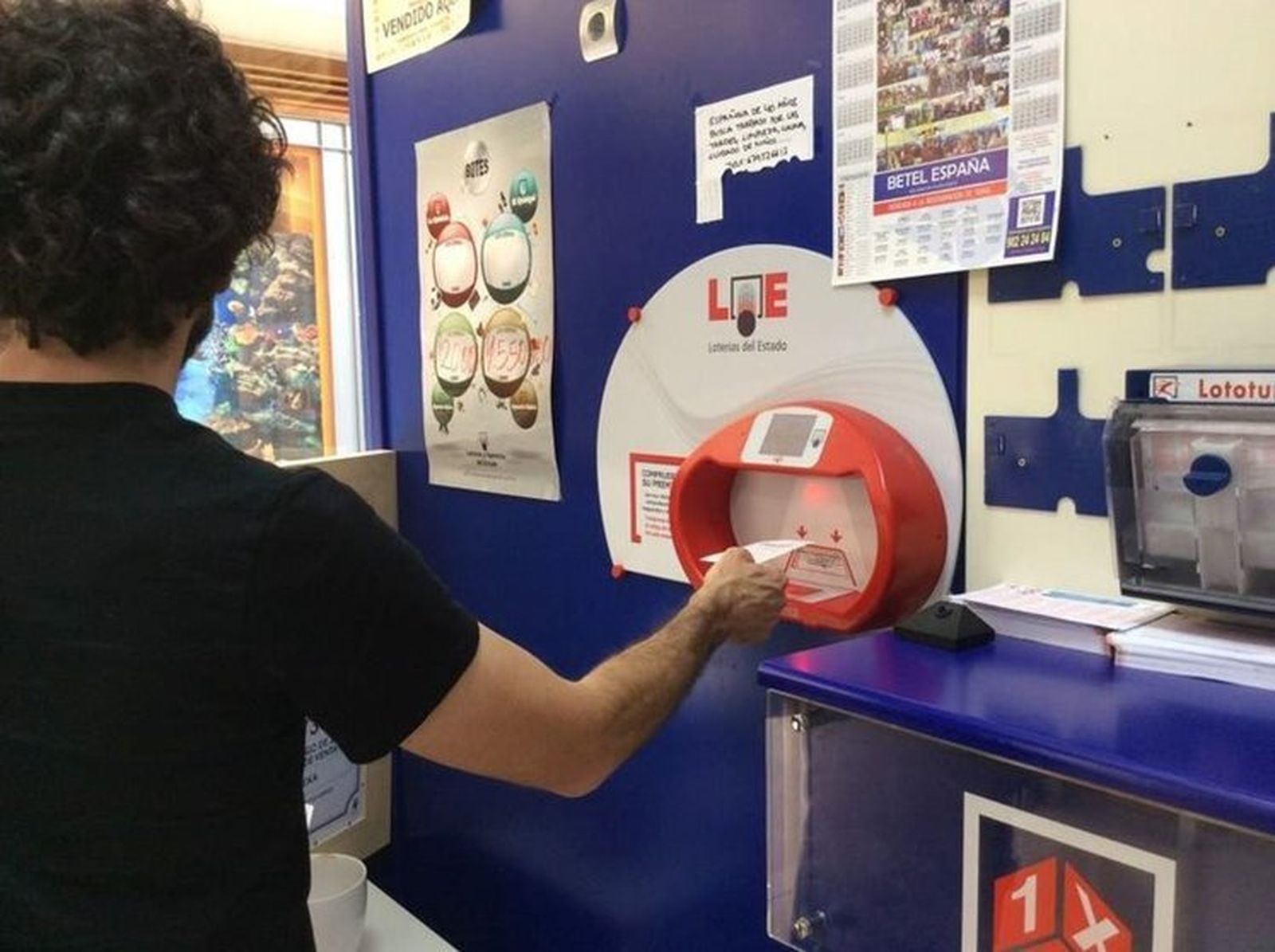 Una persona comprueba su boleto en un despacho de Loterías.