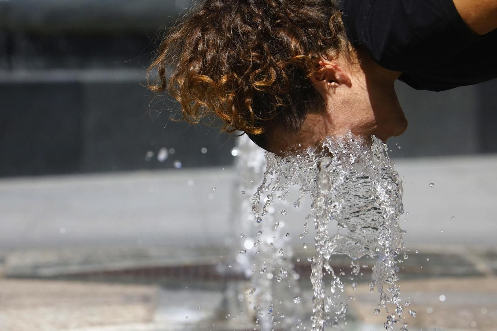Una mujer se refresca en una fuente durante la ola de calor