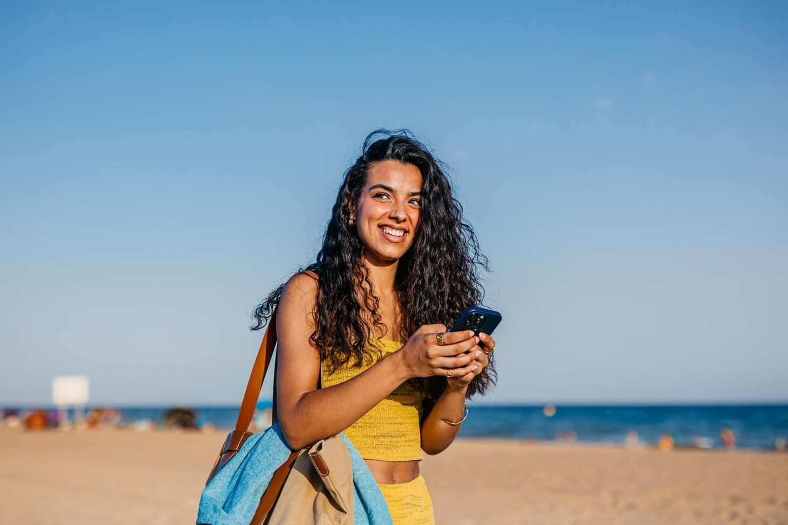 Una joven usa su móvil en una playa.