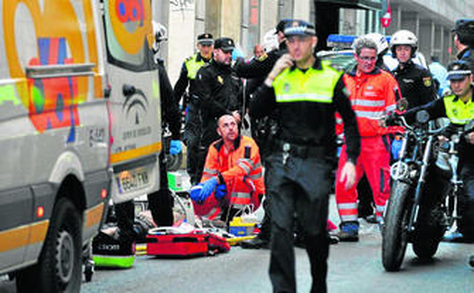 Los policías retiran el vehículo  mientras en el suelo los sanitarios intentan mantener con vida al conductor accidentado.