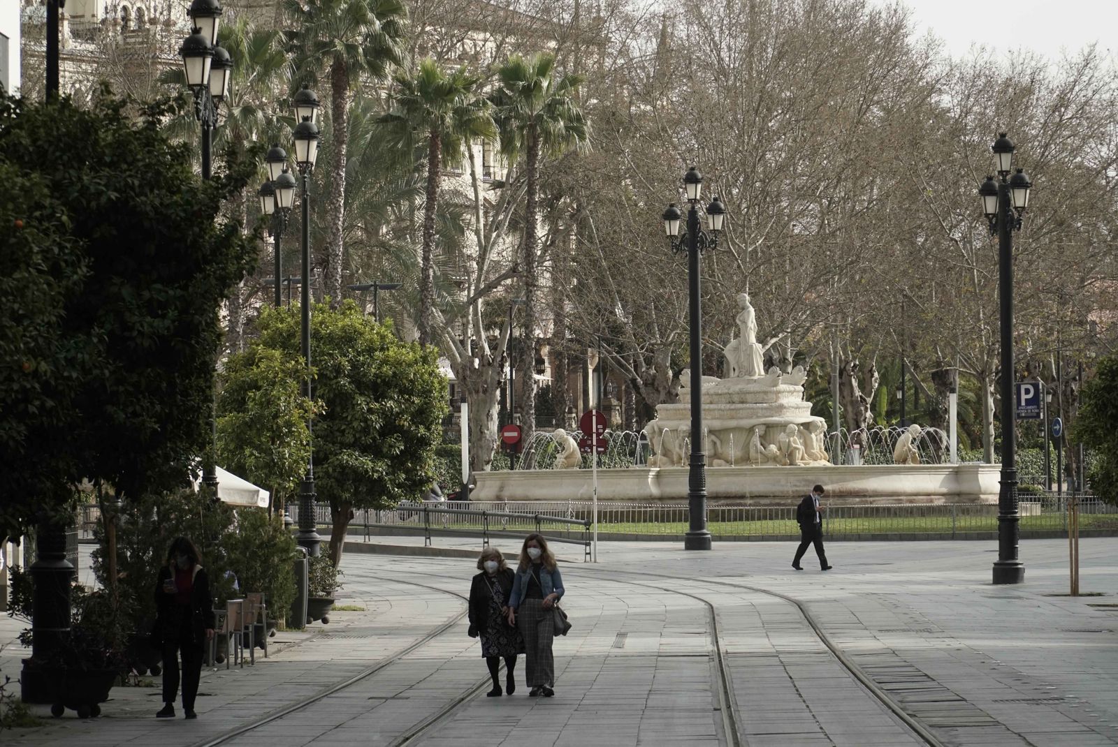 Varias personas caminan por la Avenida con la fuente de la Puerta de Jerez al fondo.