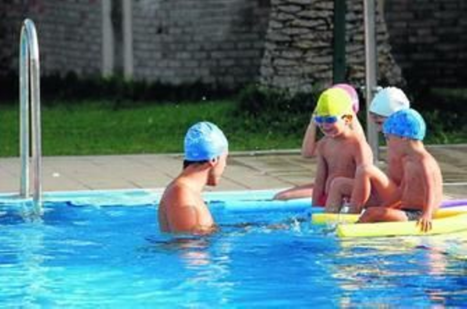 Uno de los monitores junto a varios niños de los cursos de natación en la piscina del polideportivo Tiro de Linea, esta temporada.
