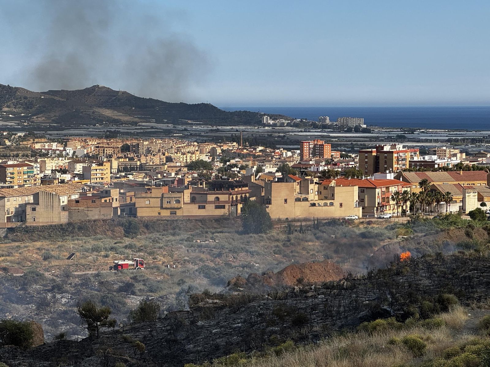 Los bomberos actuando en la zona con Motril de fondo