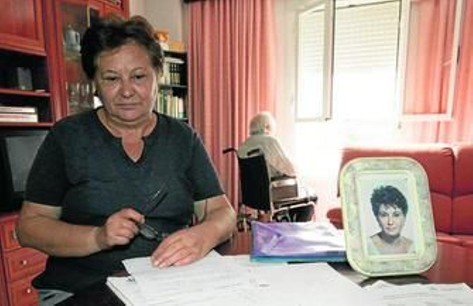 Carmen Vega, con su padre al fondo y entre papeles, en su piso de la calle Valencia, de Cádiz.