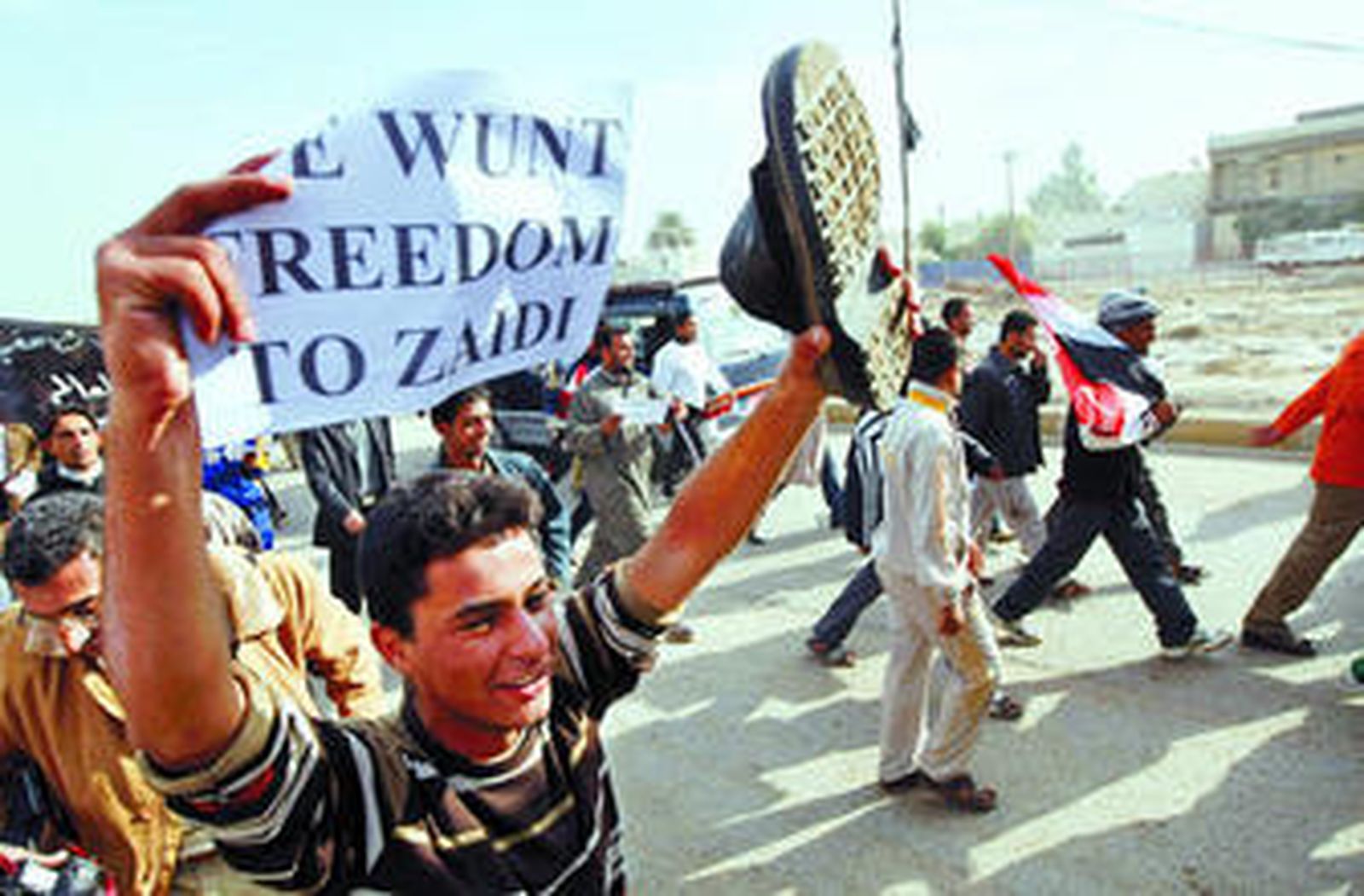 Un iraquí grita mientras sostiene una zapatilla durante una protesta contra la visita de Bush y el arresto del periodista que le lanzó el zapato.