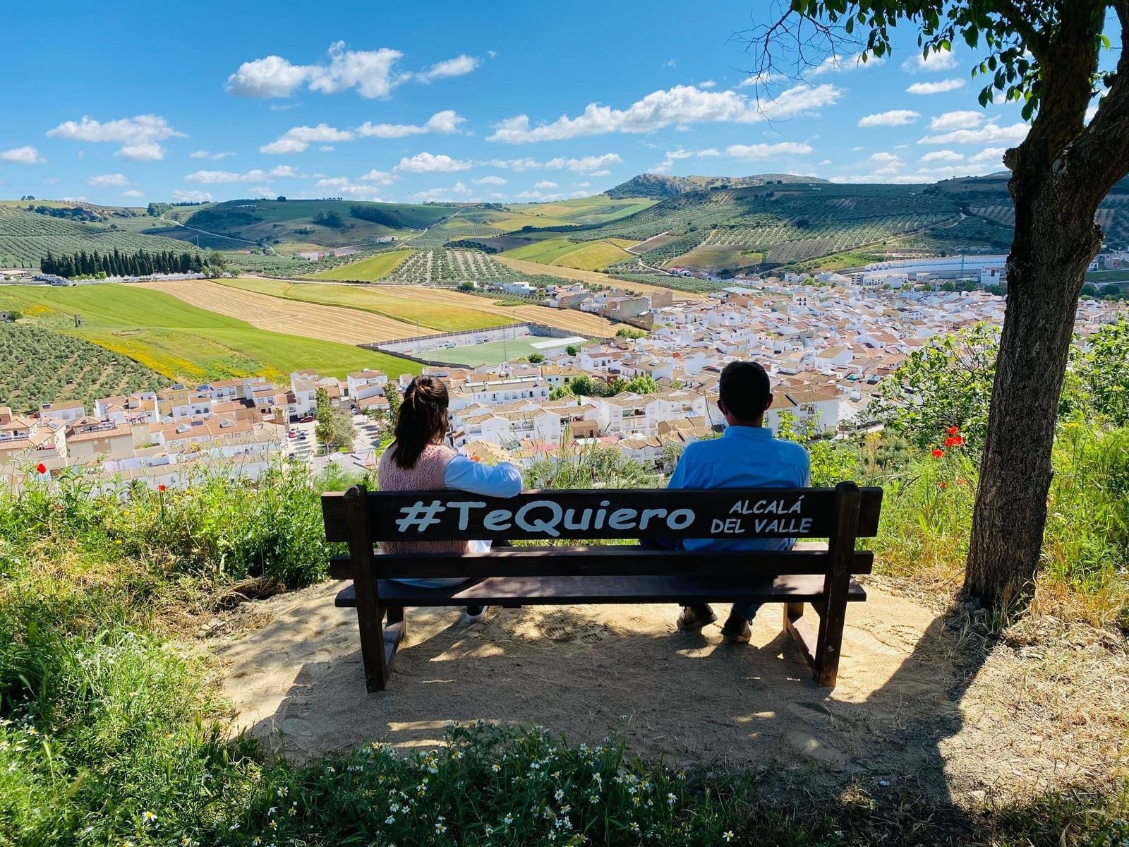 Varias personas desde un banco mirando las vistas del pueblo.