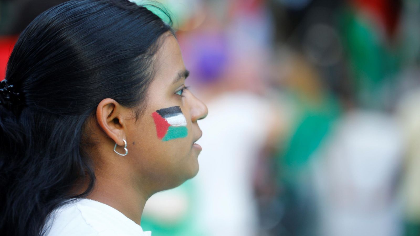 Una joven manifestante luce los colores de la bandera de Palestina en su rostro.