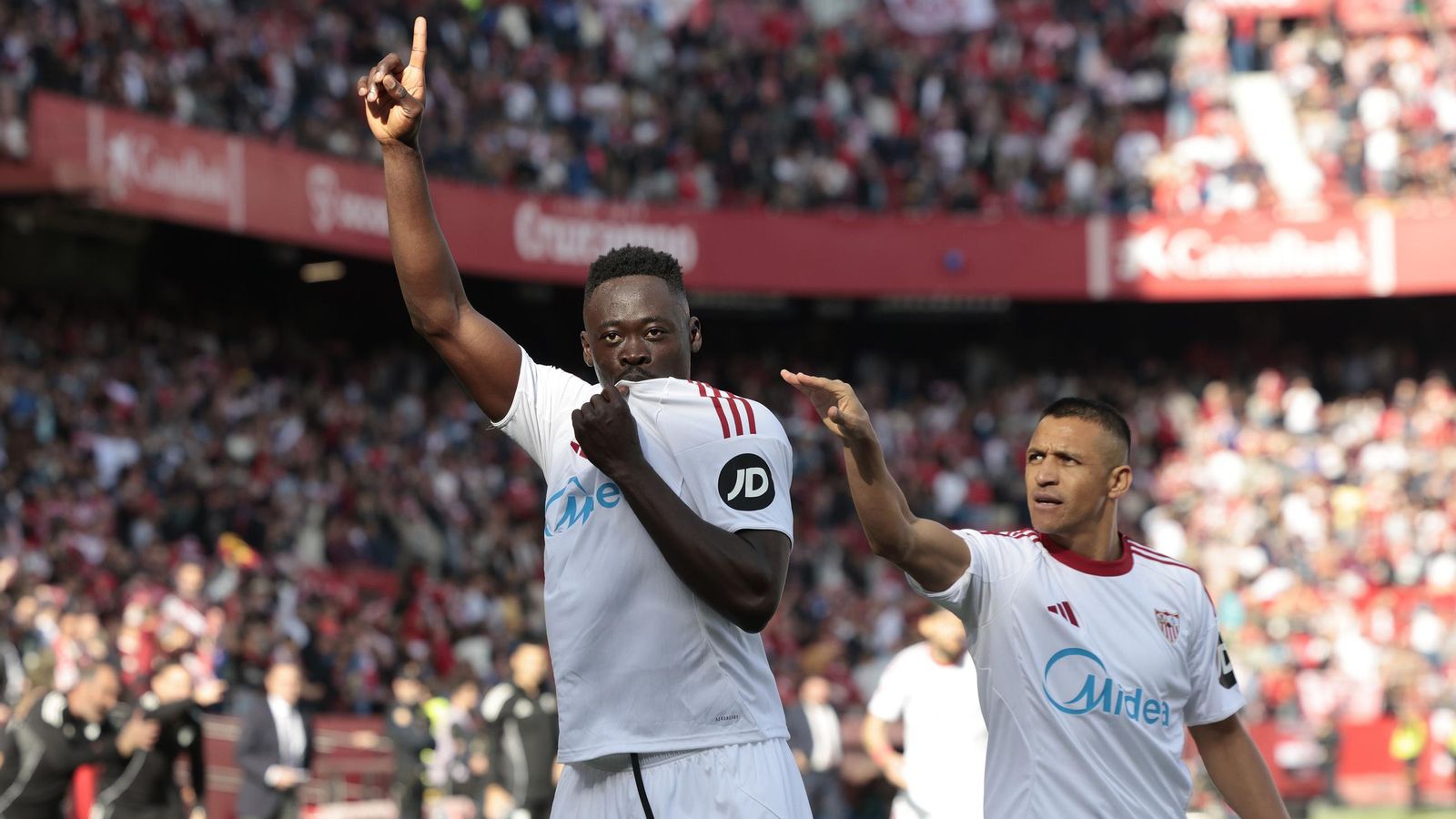 Akor Adams besa el escudo del Sevilla y Alexis se acerca a felicitarlo.