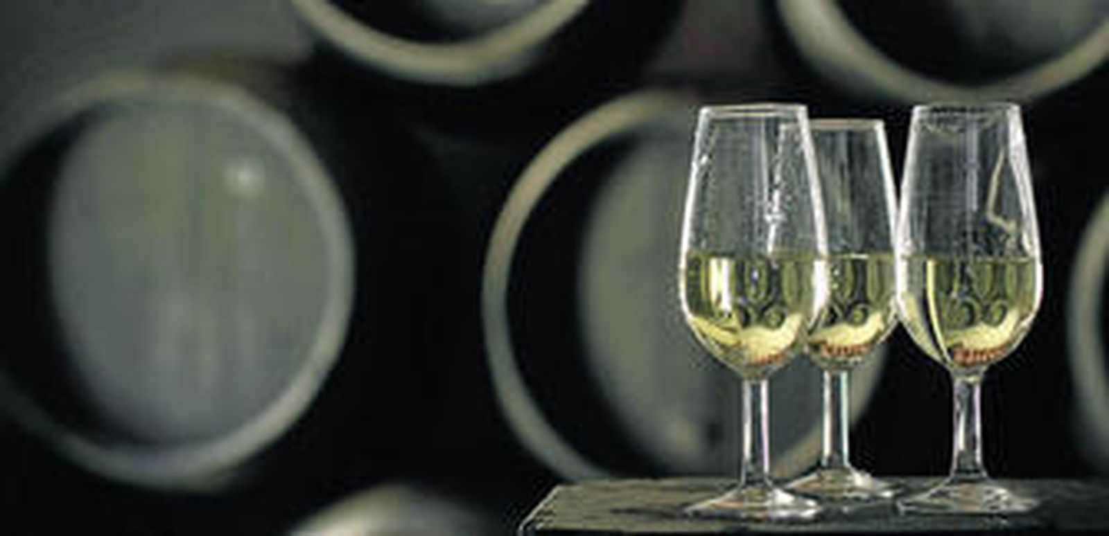 Primer plano de catavinos con botas de vino al fondo en una bodega jerezana.